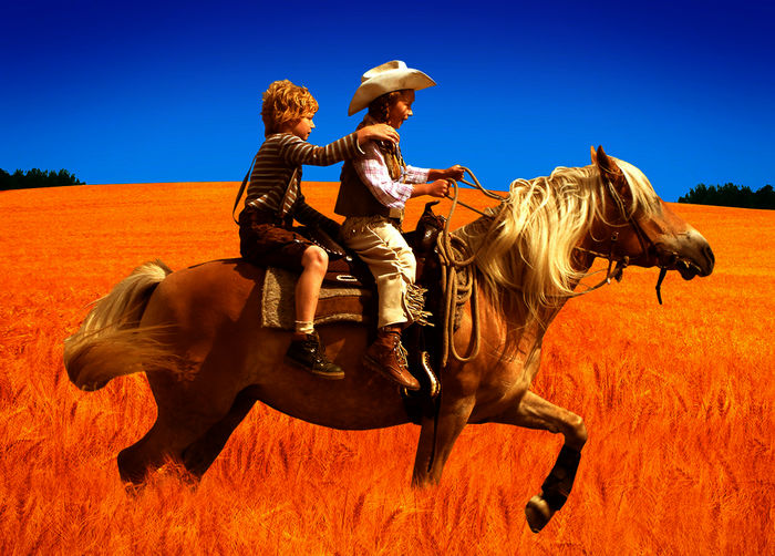 "Hände weg von Mississippi": Emma (Zoë Charlotte Mannhardt) und Leo (Karl Alexander Seidel) reiten bei strahlend blauem Himmel auf dem Pferd Mississippi durch ein goldgelbes Getreidefeld. Bild: Sender / Wolfgang Jahnke