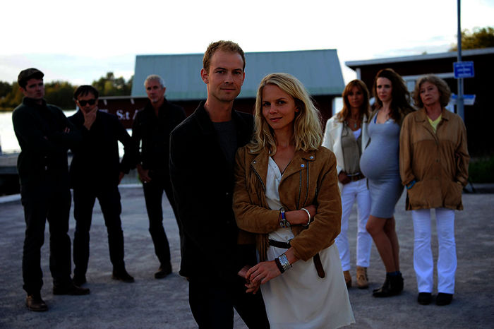 Magnus Blomquist (Christian Clau&szlig;) und Lilith Larson (Sinja Dieks) stehen am Hafen und halten sich an den H&auml;nden. Hinter den beiden stehen die Blomquists, Nils (Frederic Welter), Peter (Peter Davor) und Thor (Markus B&ouml;ker), und Rhea (Carin C. Tietze), Diana (Julia Malik) und Iris (Lisa Kreuzer) und beobachten Magnus und Lilith skeptisch. Bild: Sender / ZDF / Bernd Spauke